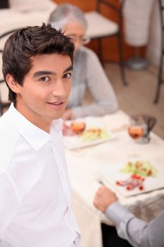 Young waiter serving lunch