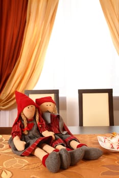 on a table two dolls against a window sit