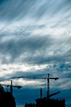 Small silhouettes of cranes with beautiful and dramatic cloudscape background