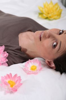 Woman lying on a bed surrounded by flowers