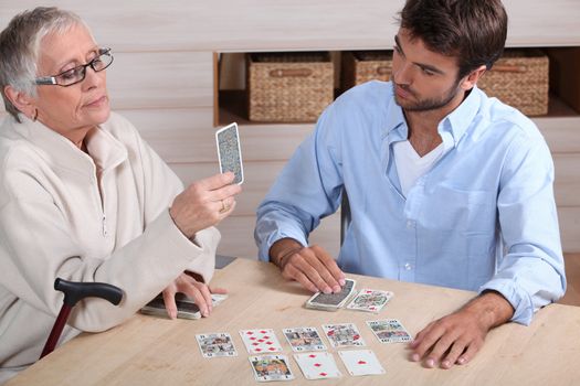 young man playing cards with older woman