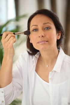 Thirty years old woman applying blush