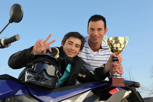 A young biker with a trophy.