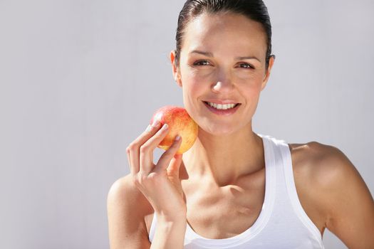 Brunette holding red apple to face