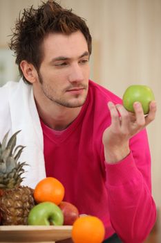 Young man picking an apple from a fruit bowl