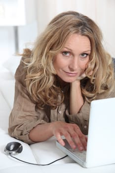 mature woman relaxing on the couch with her laptop