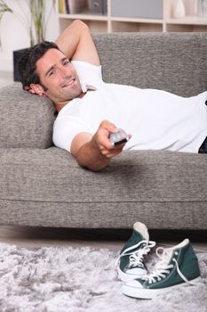 Man lying on couch at home watching television