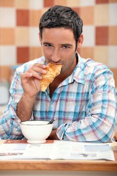 Handsome man eating a croissant