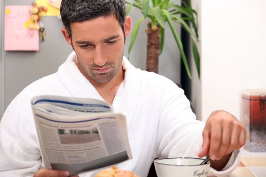 Man having a leisurely breakfast while reading the paper