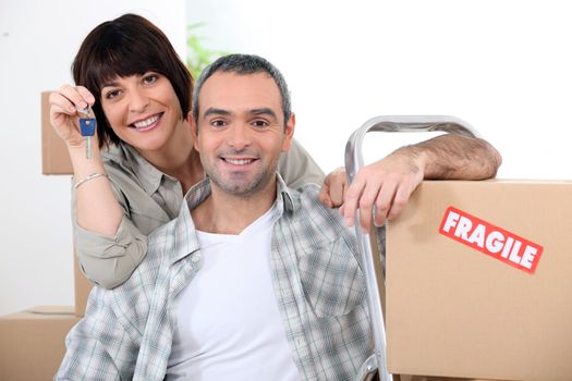 Couple moving into new home with doorkeys and boxes marked fragile