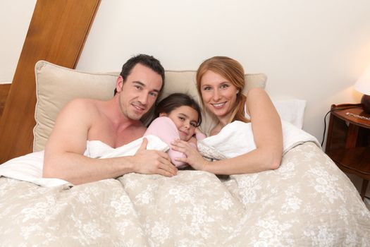 Parents and daughter in bed