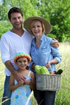 Parents and young daughter with basket of vegetables