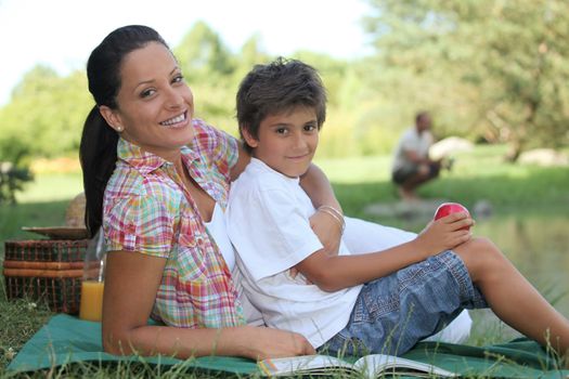 a mother and her son at picnic, the father is fishing