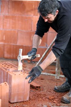 Builder hammering a brick