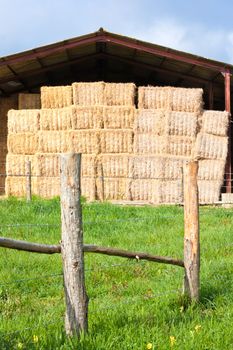 Haystack stored on a French farm with a fence in the foreground