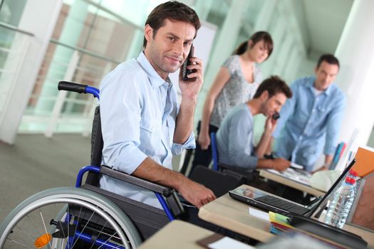 Man in wheelchair with mobile phone at work