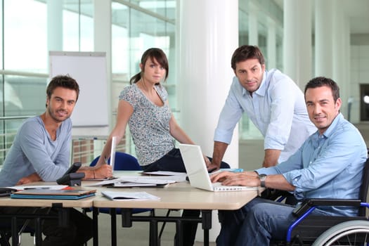 Man in wheelchair sat at desk with colleagues