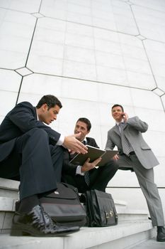 Businessmen sitting outside a city building