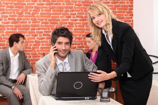 Waitress in a restaurant helping a man with his laptop computer