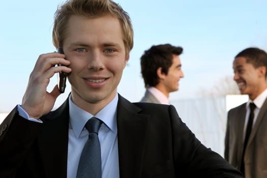 Young businessman on the phone in front of colleagues