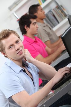 male students in class working on laptop