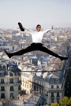 Businessman jumping for joy on a tightrope
