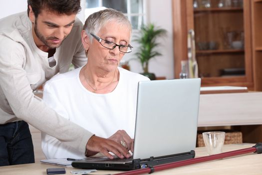 Young man helping a senior with a laptop computer