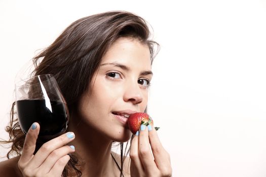 Portrait of a beautiful, latin Woman eating a Strawberry and drinking wine.