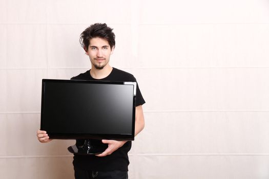 A young hispanic man holding a flatscreen TV.