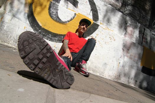 A Rapper leaning against a Graffiti wall.