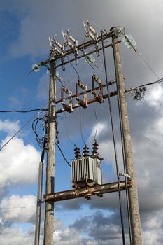 Electric transformer substation against a blue sky with white clouds
