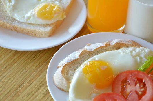 american style breakfast , with toast,  fried egg and fresh vegetables , milk and orange juice
