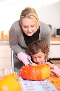 Mother and daughter carving jack-o-lanterns