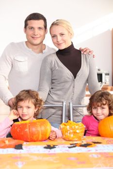 Family gathered around kitchen table preparing pumpkins