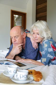 Elderly couple having breakfast in bed