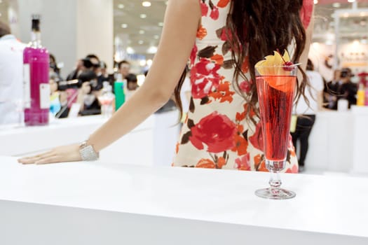 A tall glass of cocktail "Eliza" with a girl on background