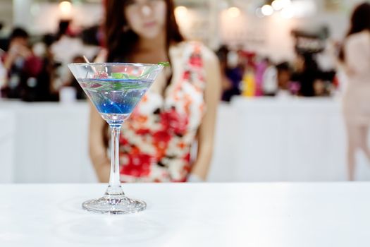A glass of blue cocktail (Ole) with sexy girl on background