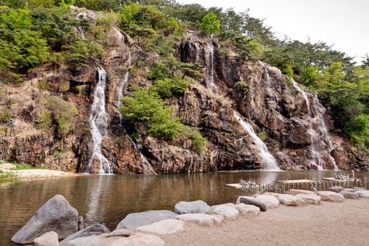 Artificial waterfalls in public park in sunny day