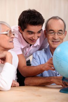 grandparents ant their grandson looking at a globe