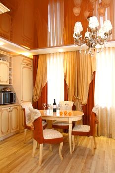 beautiful interior of kitchen with a table, a bottle of wine and glasses, a floor-to-ceiling window with a curtain, a vertical shot