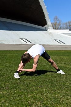 Runner at the city stadium warming and stretching