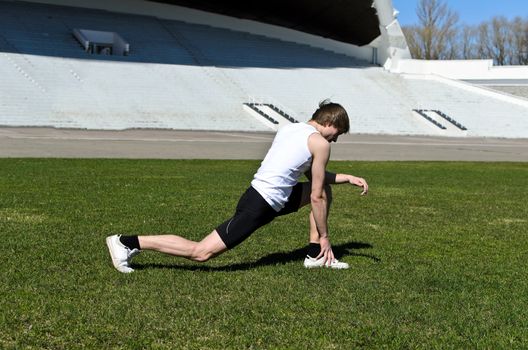 Runner at the city stadium warming and stretching