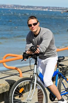 Portrait of handsome male with bicycle by the sea