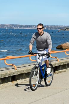 Portrait of handsome male riding a bicycle by the sea