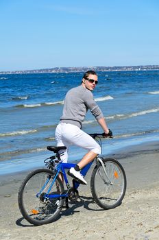 Portrait of handsome male riding a bicycle by the sea