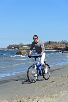 Portrait of handsome male riding a bicycle by the sea
