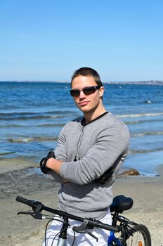 Portrait of handsome male with bicycle by the sea
