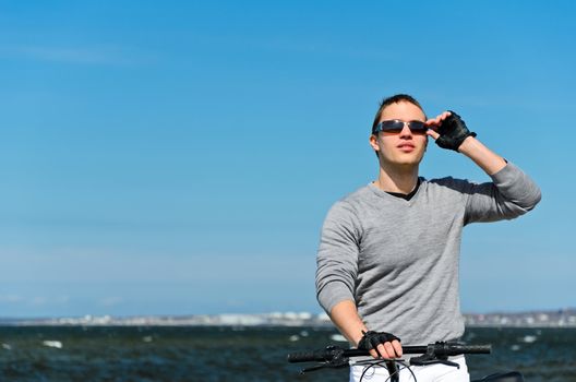 Portrait of handsome male with bicycle by the sea