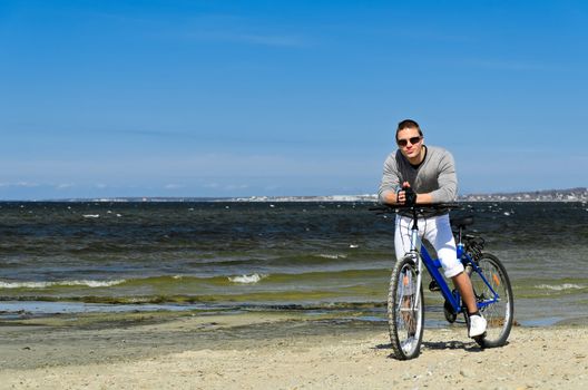 Portrait of handsome male with bicycle by the sea