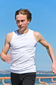 Athletic young male running on the shoreline